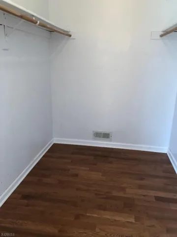 a view of an empty room with wooden floor and closet