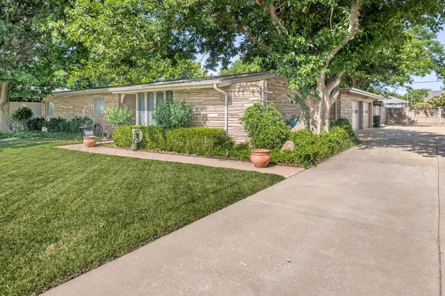 a view of a house with a yard and potted plants