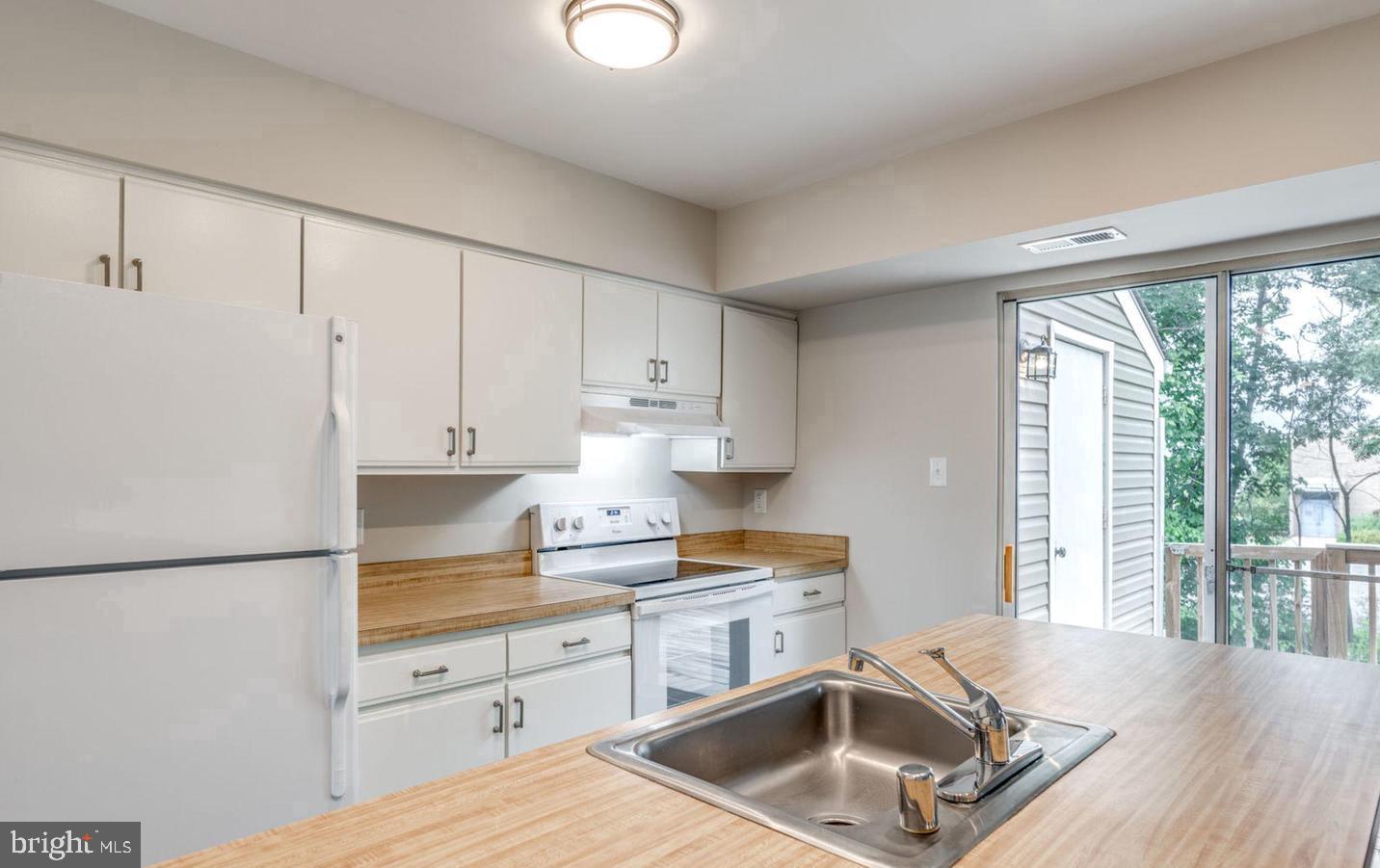340 Lancaster Square Sterling, VA 20164 - Photo 5 of 12 a kitchen that has a sink a stove and white cabinets with wooden floor