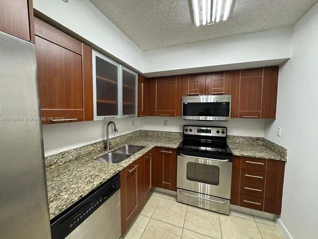 a kitchen with stainless steel appliances granite countertop wooden cabinets a stove and a sink