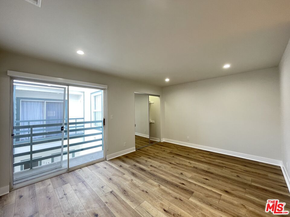 11738 Mayfield Avenue, Unit 114 Los Angeles, CA 90049 - Photo 16 of 25 an empty room with wooden floor and windows
