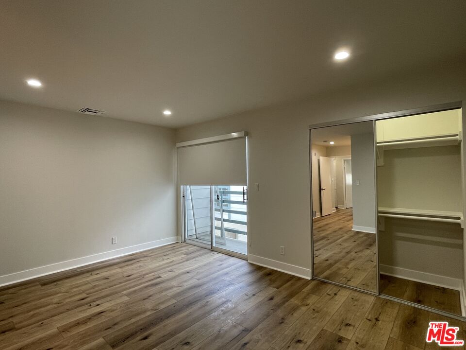 11738 Mayfield Avenue, Unit 114 Los Angeles, CA 90049 - Photo 17 of 25 an empty room with wooden floor & windows