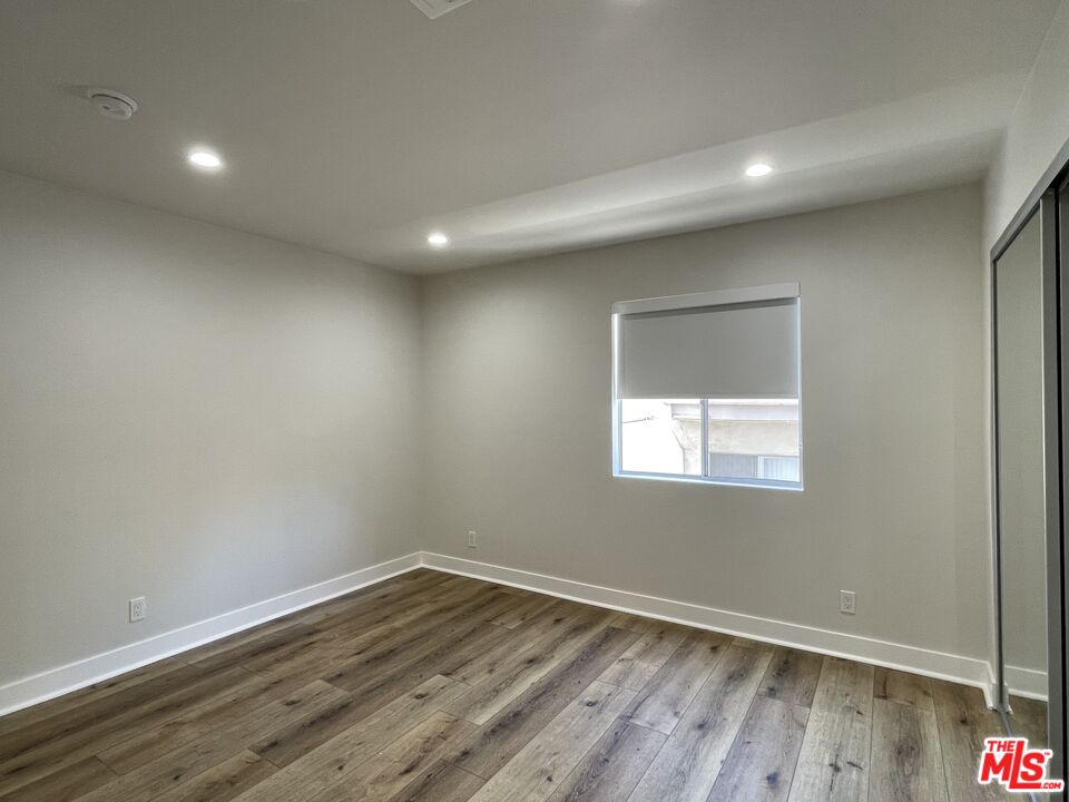 11738 Mayfield Avenue, Unit 114 Los Angeles, CA 90049 - Photo 20 of 25 an empty room with wooden floor and windows