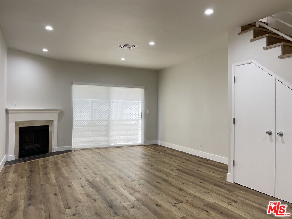 11738 Mayfield Avenue, Unit 114 Los Angeles, CA 90049 - Photo 8 of 25 an empty room with wooden floor fireplace and windows