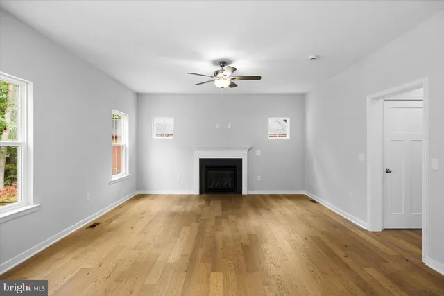 a view of empty room with wooden floor and fireplace