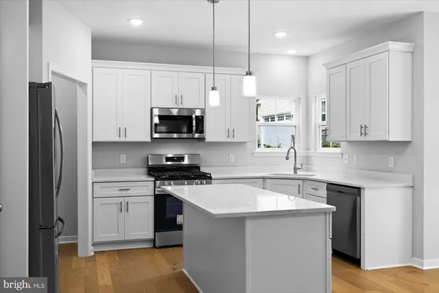 a kitchen with stainless steel appliances a stove a sink a refrigerator and white cabinets