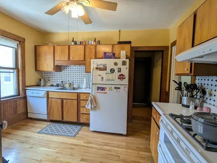 a kitchen with stainless steel appliances granite countertop a refrigerator a sink dishwasher a stove and a dining table with wooden floor