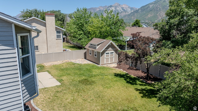 11957 Noelle Road Sandy, UT 84092 - Photo 33 of 38 Expansive backyard featuring a detached shed with dormer, manicured lawn, established landscaping, and mountain scenery