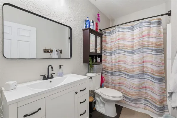 a bathroom with a sink a toilet and shower curtain