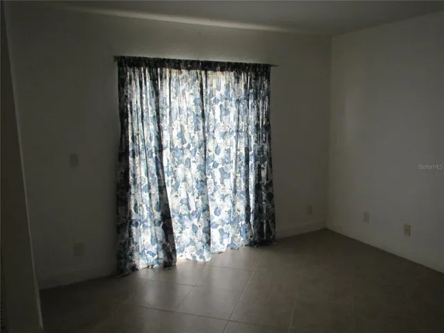 an empty room with wooden floor and windows with curtains