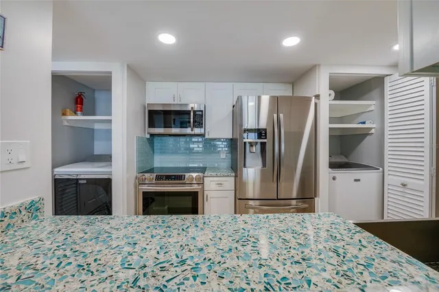 a kitchen with granite countertop a refrigerator and a stove top oven