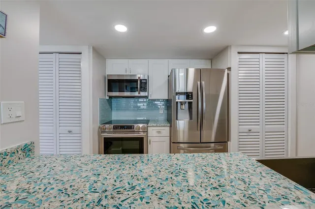 a kitchen with stainless steel appliances granite countertop a refrigerator and a stove