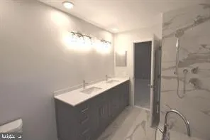 a bathroom with a double vanity sink mirror and shower