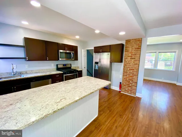 a large kitchen with stainless steel appliances wooden floors and wooden cabinets