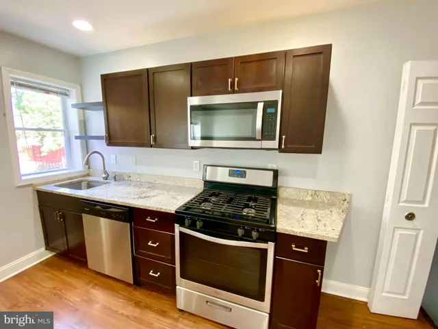 a kitchen with granite countertop stainless steel appliances a stove sink and microwave
