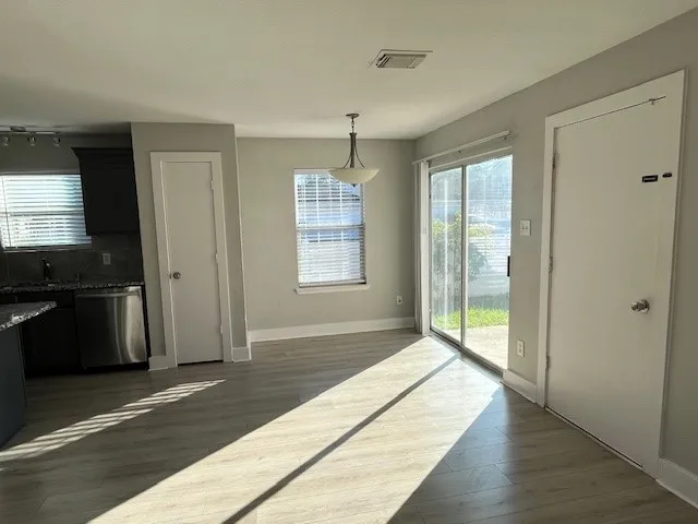 a view of an empty room with window and wooden floor