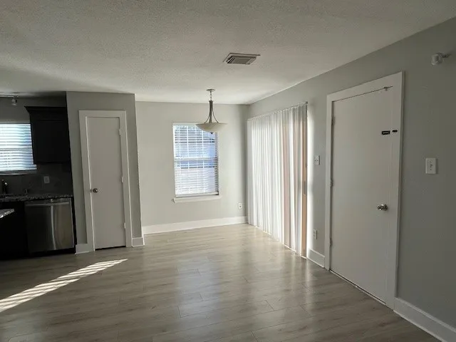 an empty room with wooden floor cabinet and front door