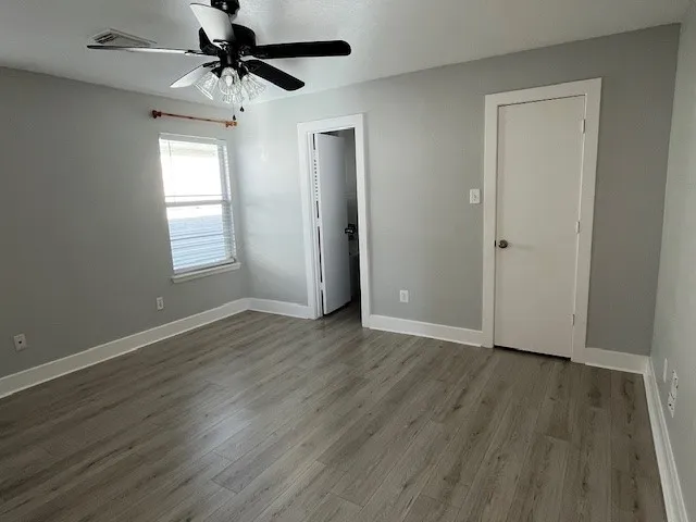 an empty room with wooden floor closet and windows