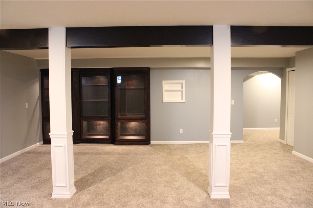 202 Home Street Rittman, OH 44270 - Photo 29 of 47 Expansive carpeted area featuring architectural columns, built-in display cabinetry with integrated lighting, a recessed wall niche, and an arched doorway
