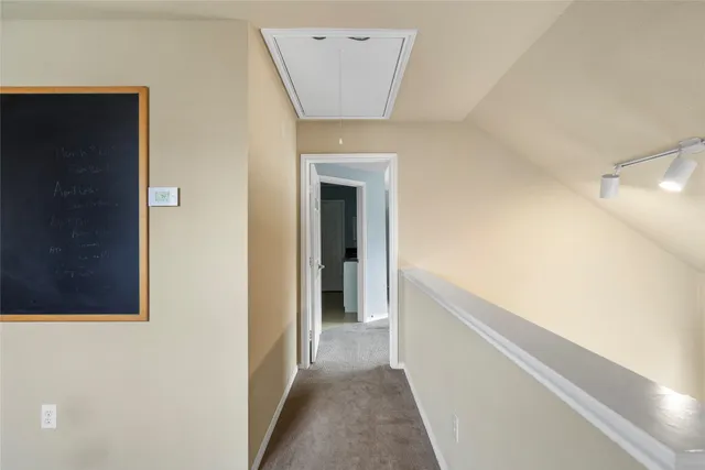 a view of a hallway with wooden floor and a bathroom