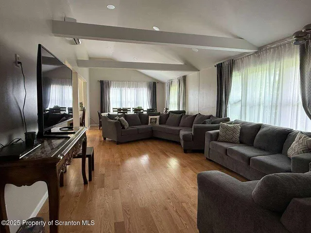 a living room with furniture kitchen view and a wooden floor