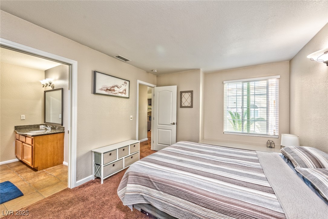 3145 East Flamingo Road, Unit 2068 Las Vegas, NV 89121 - Photo 12 of 15 Bedroom with a textured wall, light carpet, a textured ceiling, and light tile patterned flooring