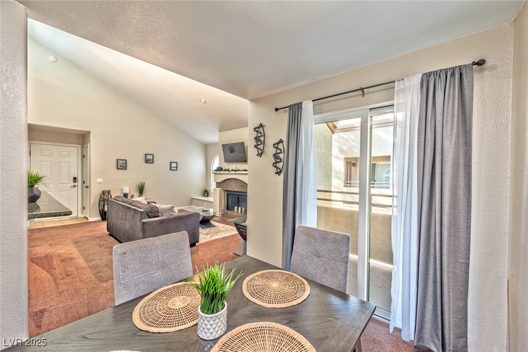 3145 East Flamingo Road, Unit 2068 Las Vegas, NV 89121 - Photo 7 of 15 Carpeted dining room featuring vaulted ceiling and a fireplace
