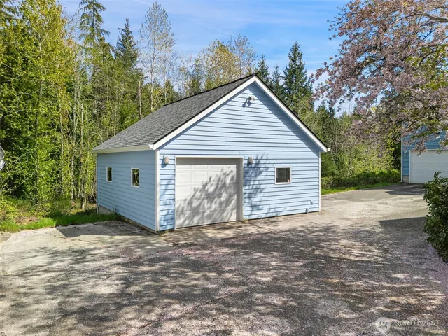 a view of a small house with a small yard and large trees