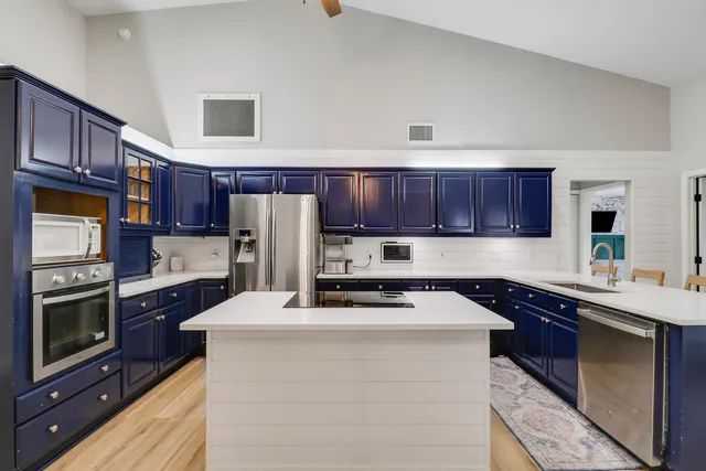 a kitchen with stainless steel appliances a sink a stove a refrigerator cabinets and a center island