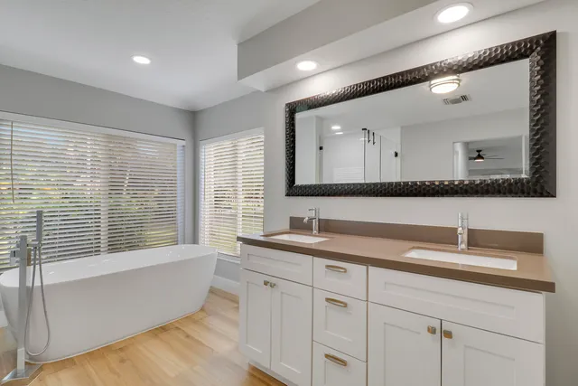 a bathroom with a sink mirror and a bathtub next to a window
