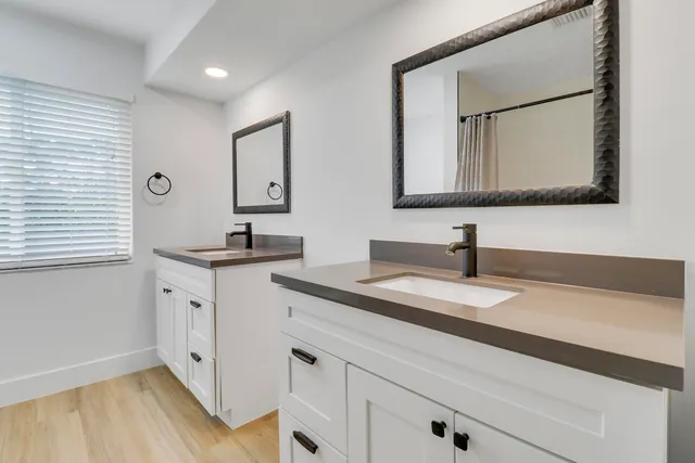a bathroom with a granite countertop double vanity sink and mirror
