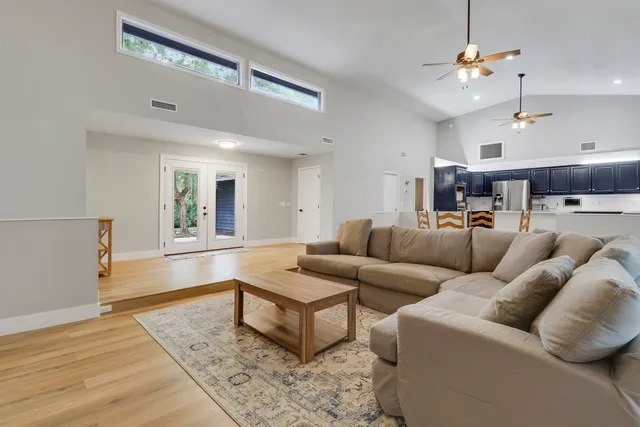 a living room with furniture kitchen view and a chandelier