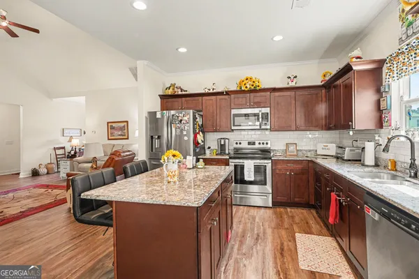 a kitchen with stainless steel appliances granite countertop a sink stove refrigerator and cabinets
