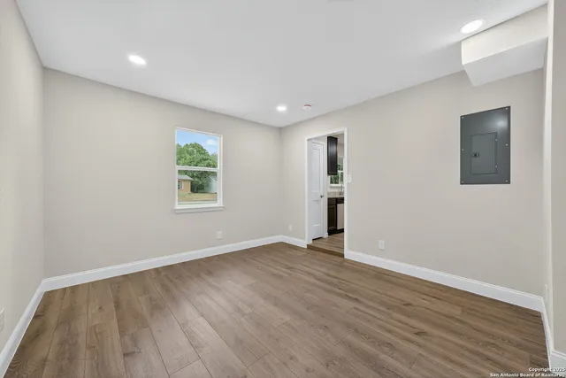 an empty room with wooden floor and windows
