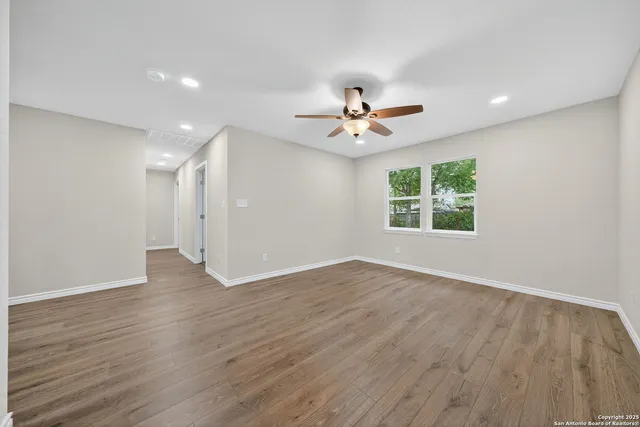 an empty room with wooden floor and windows