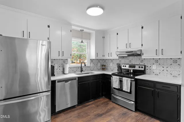 a kitchen with stainless steel appliances granite countertop a refrigerator a sink a stove and white cabinets