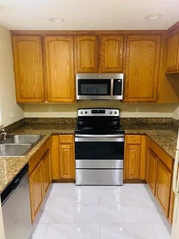 a kitchen with granite countertop wooden cabinets stainless steel appliances and a counter space