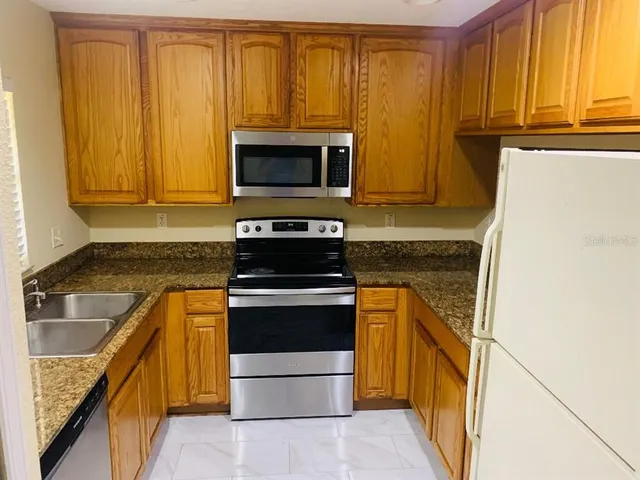 a kitchen with granite countertop cabinets stainless steel appliances and a counter space