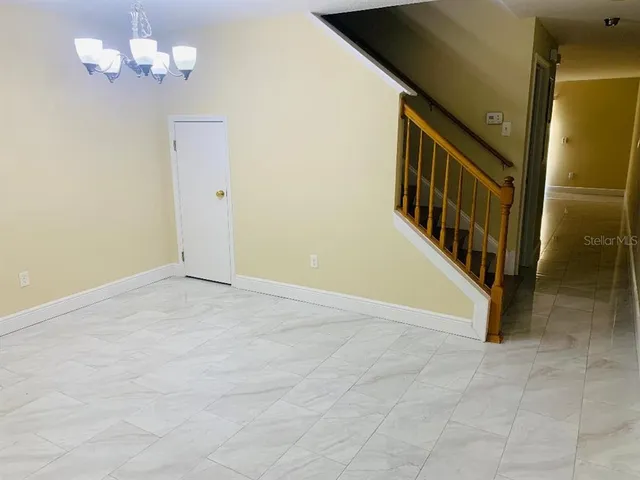 a view of an empty room with chandelier fan