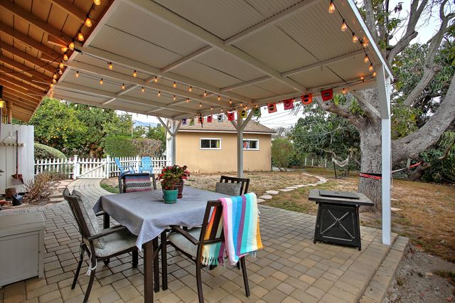 a view of a patio with a table and chairs under an umbrella with a barbeque