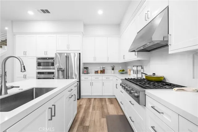a kitchen with stainless steel appliances a stove a sink and white cabinets