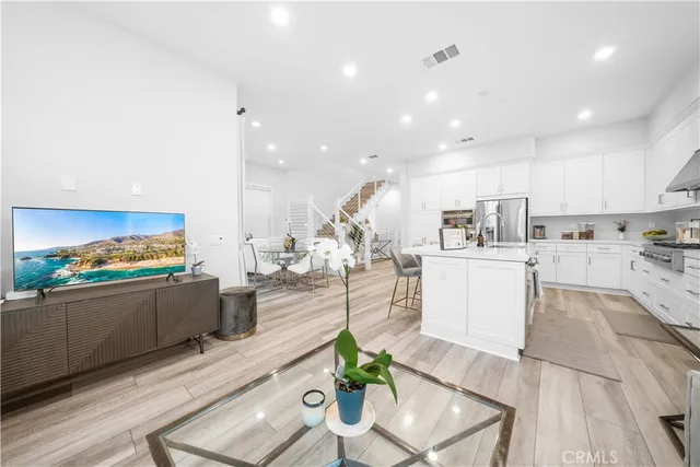 a living room with stainless steel appliances furniture a rug kitchen view and a faucet