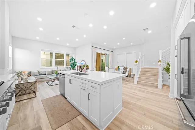 a large white kitchen with stainless steel appliances kitchen island granite countertop a large counter top a stove and a wooden floors