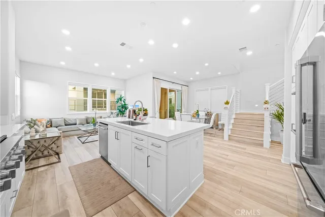 a large white kitchen with stainless steel appliances kitchen island granite countertop a large counter top a stove and a wooden floors