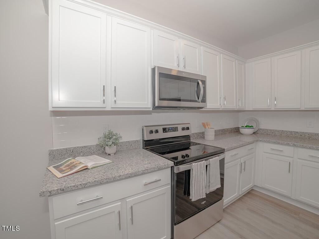 137 Rolesville Ridge Drive Rolesville, NC 27571 - Photo 6 of 17 a kitchen with granite countertop white cabinets and white appliances