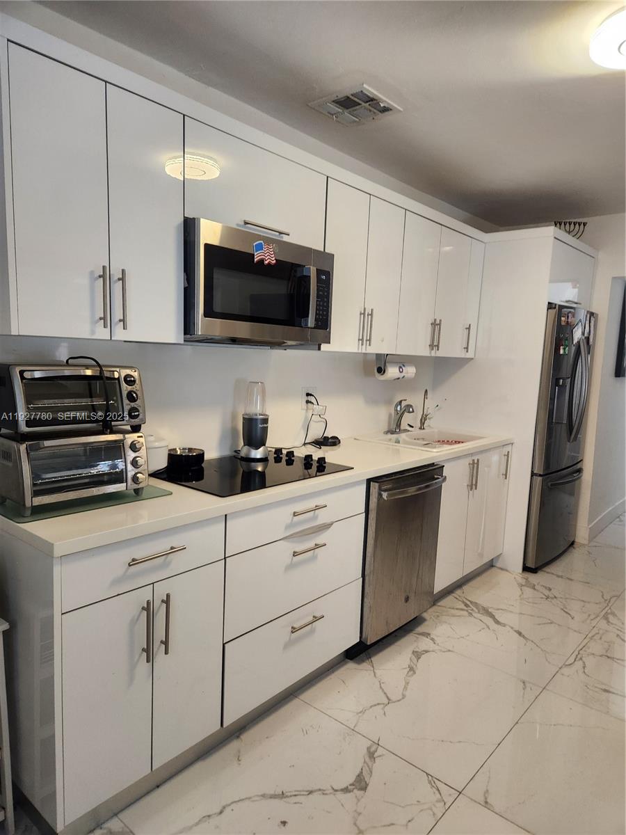 1645 Southwest 83rd Ct. Miami, FL 33155 - Photo 19 of 45 a kitchen with white cabinets stainless steel appliances and a sink
