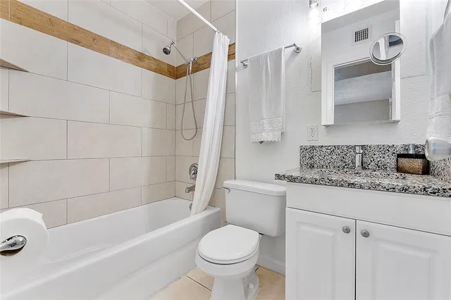 a bathroom with a granite countertop toilet a sink and bathtub