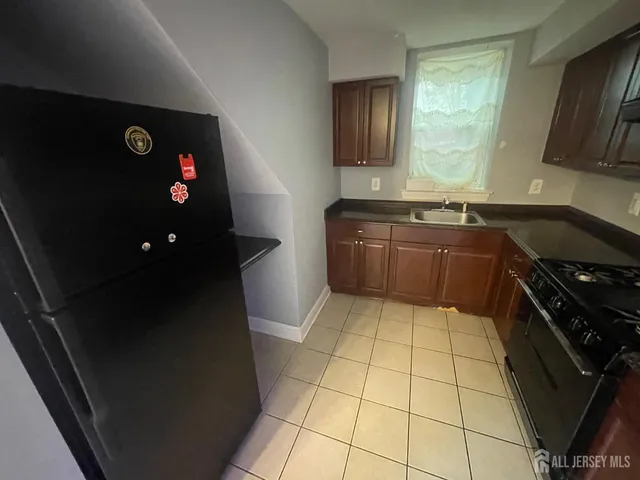a kitchen with granite countertop a stove a sink and a refrigerator