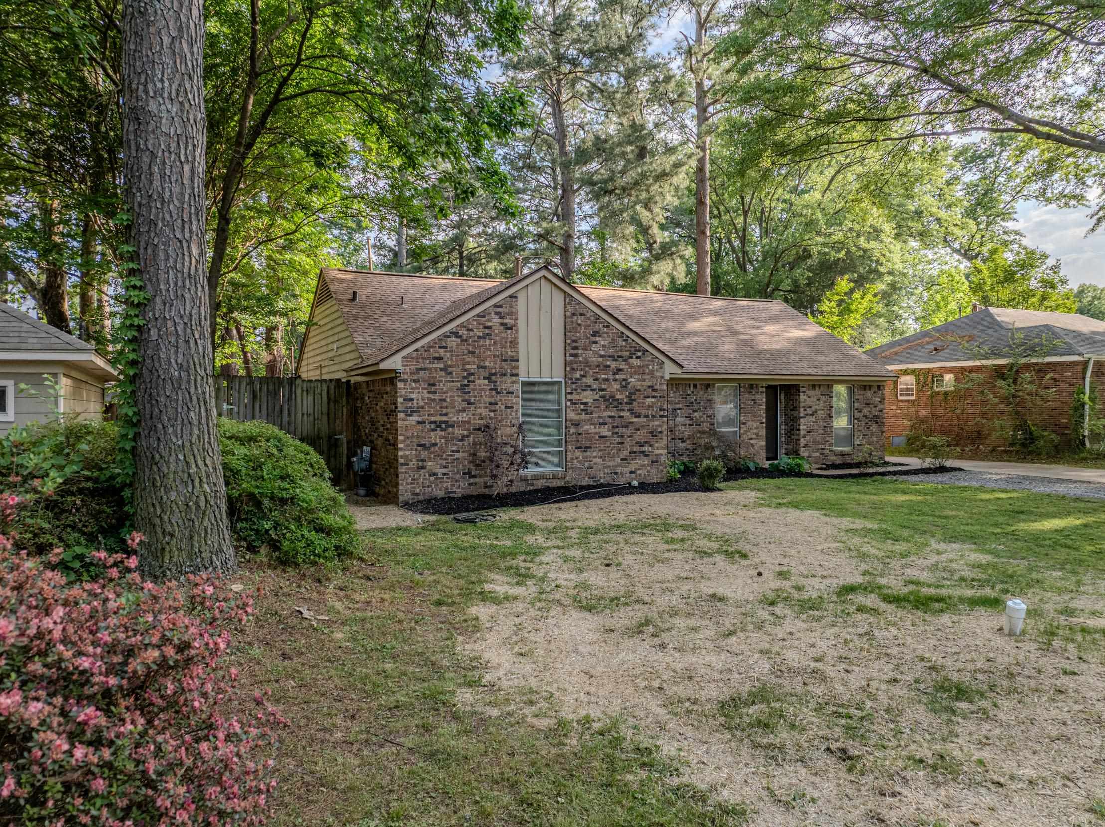 5333 Mesquite Road Memphis, TN 38120 - Photo 3 of 20 Brick exterior home featuring a gabled roofline, mature trees, and a landscaped front entry
