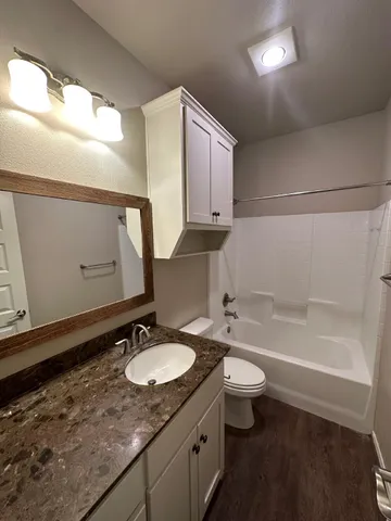 a bathroom with a granite countertop sink toilet and mirror
